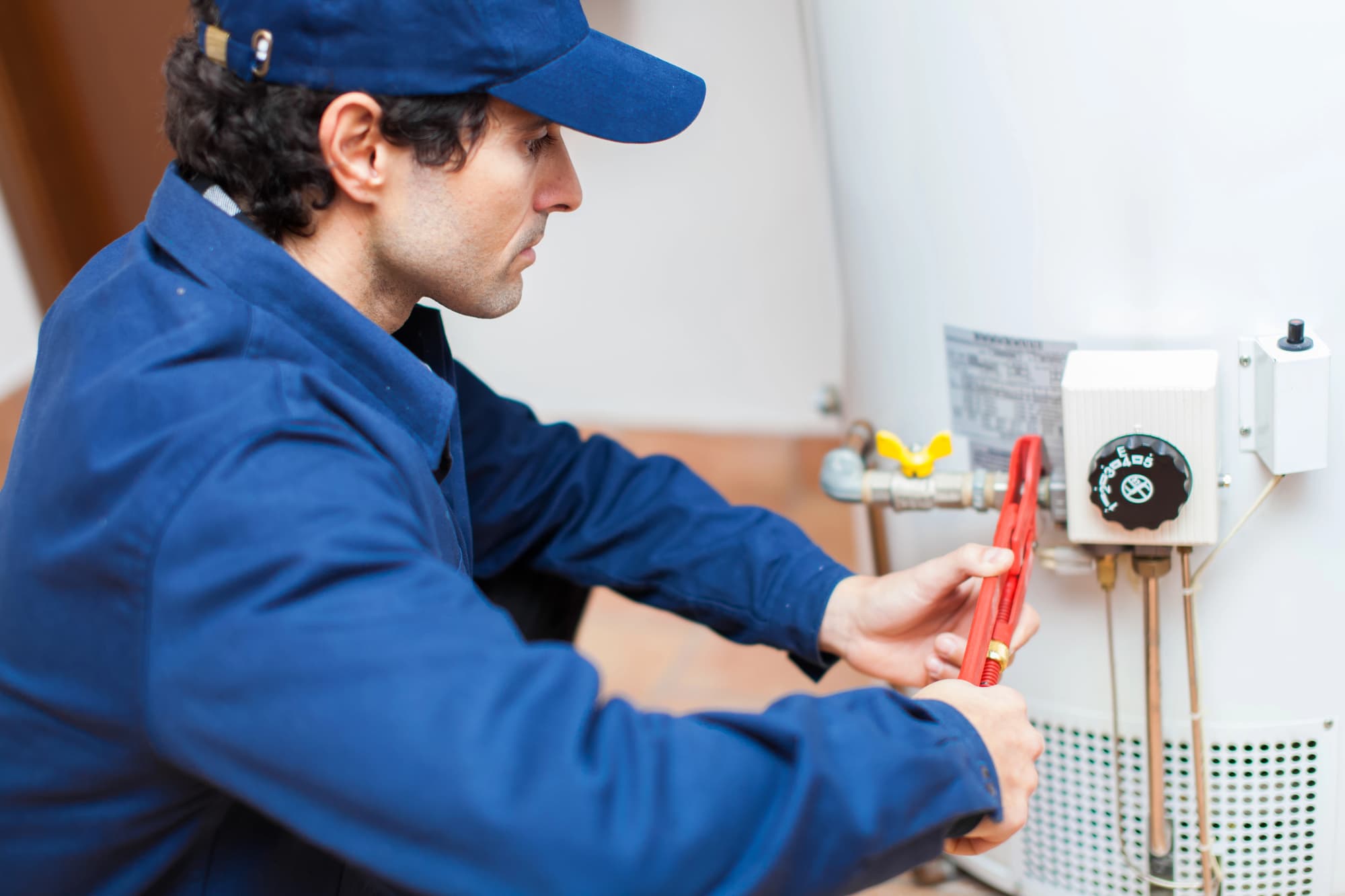 Licensed plumber inspecting a hot water tank in a Toronto home